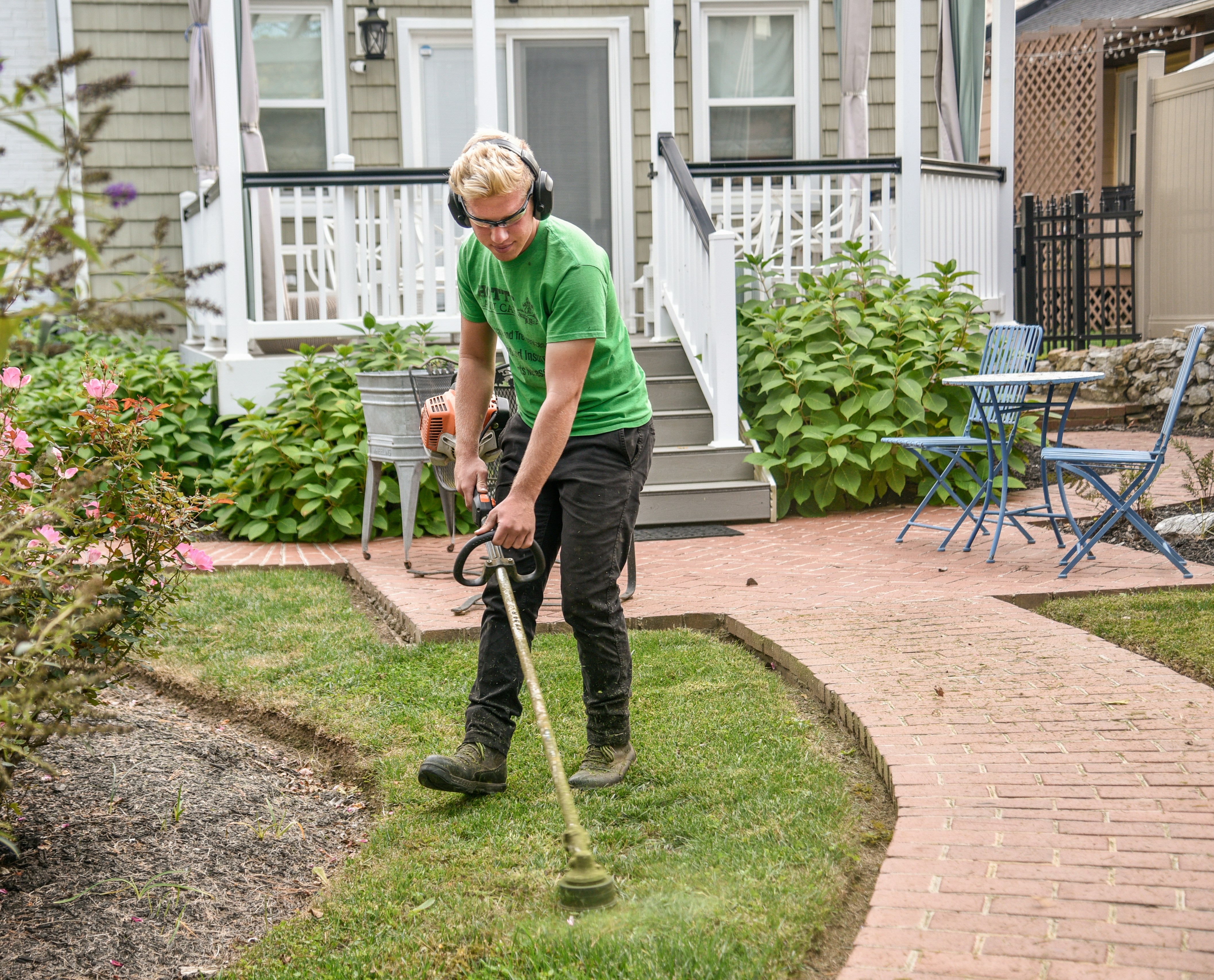 Worker trimming grass in a landscaped yard